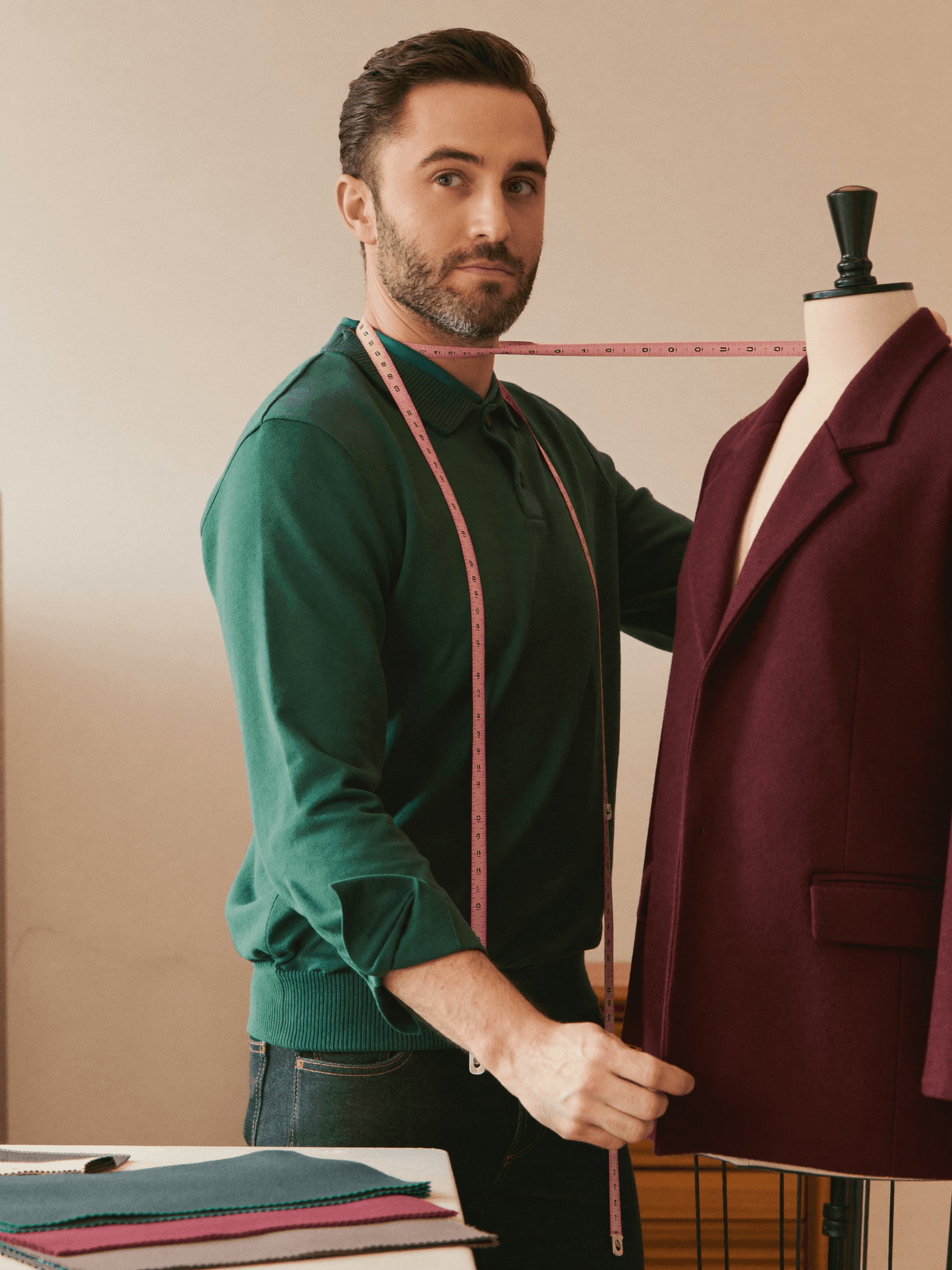 A tailor measuring and pinning a garment on a dress form